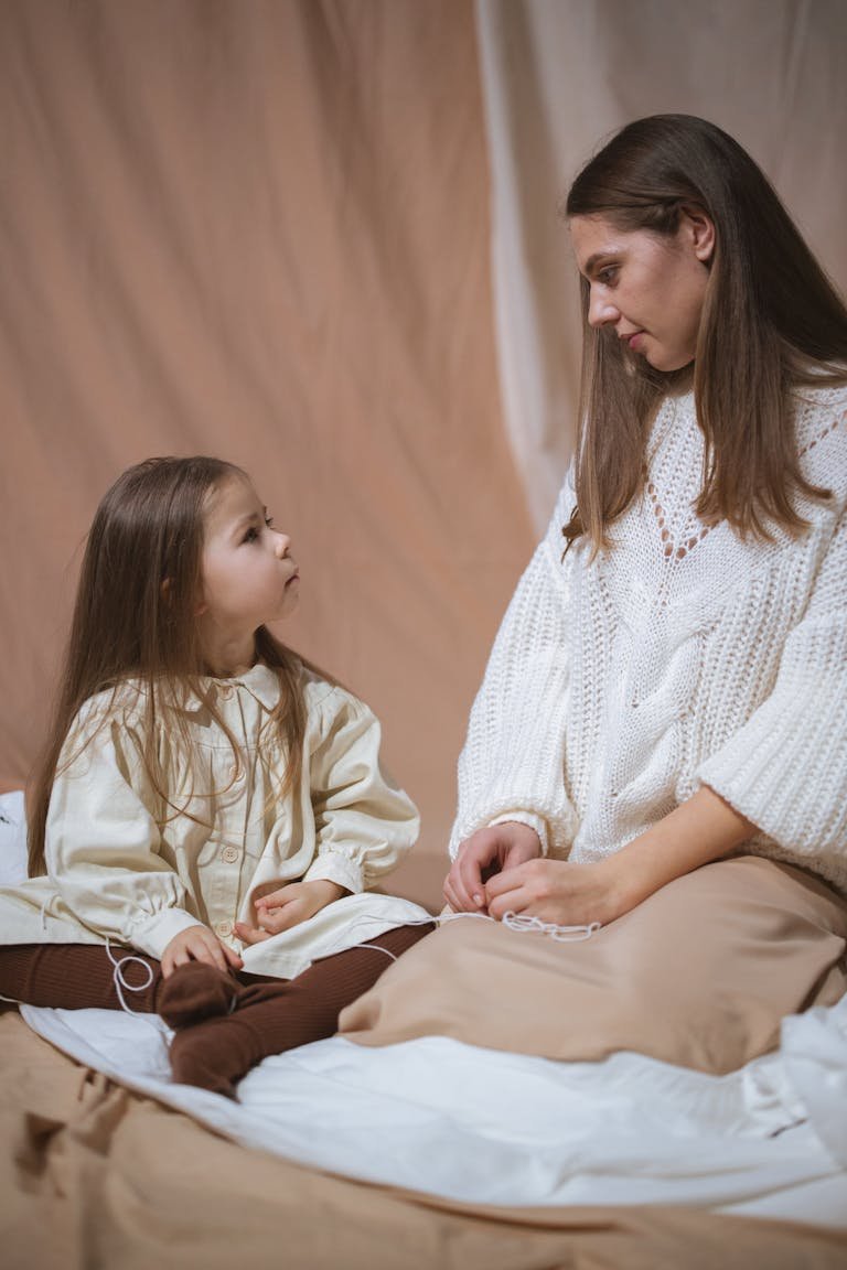 A mother and daughter sitting together indoors, sharing a warm and intimate moment.