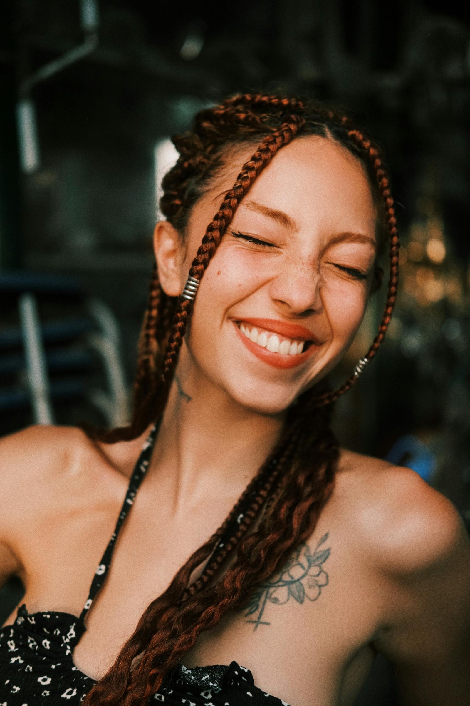 Cheerful woman with braids smiling warmly against a blurred background.