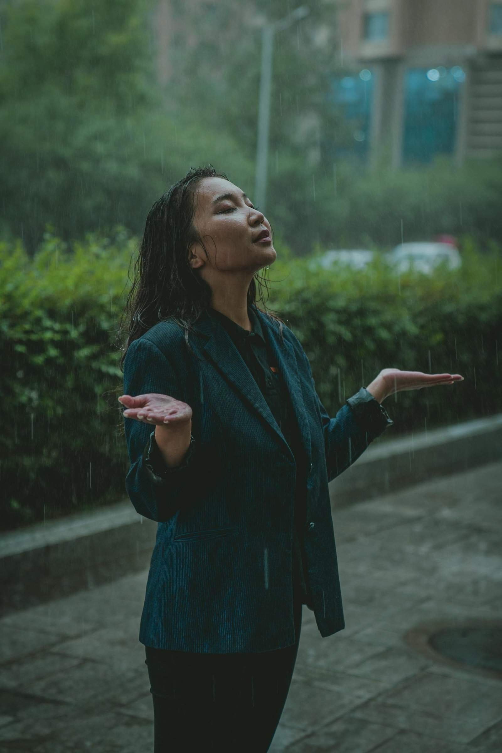 A joyful woman stands in the rain with eyes closed and arms outstretched in Ulaanbaatar, Mongolia.